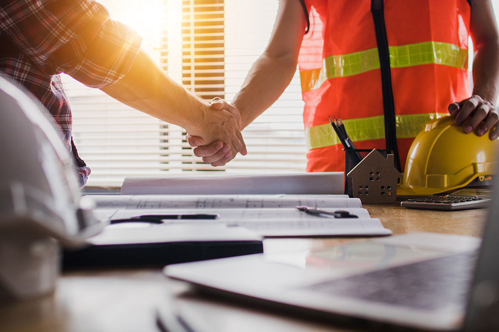 Two people shaking hands on a job site.