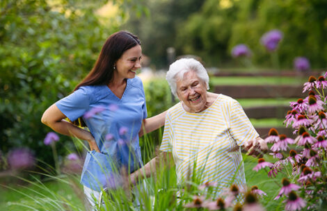 Home care nurse spending time with elderly lady patient in garden.