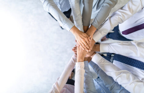 Close up top view of young business people putting their hands together.