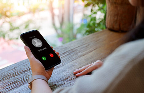 Woman holding mobile phone with incoming call from an unknown caller.