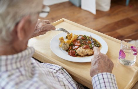 Over shoulder view of senior man eating dinner at home