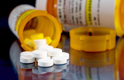 Oxycodone tablets and pills on glass table with reflections.