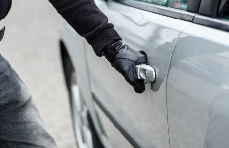 Close up on car thief hand pulling the handle of a car.