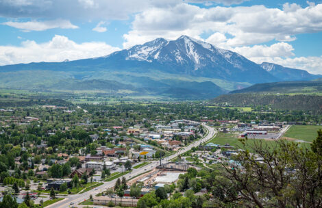 The vibrant town of Carbondale, Colorado, nestled against the majestic backdrop of snow-capped Mt Sopris under a clear blue sky.