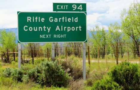 A sign showing the highway exit to the Rifle Garfield County Airport.