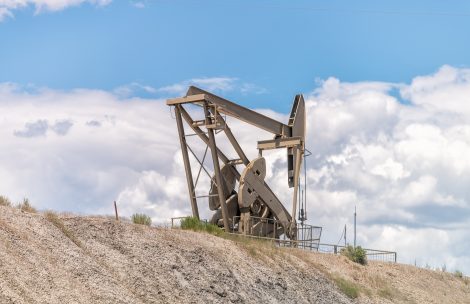A closeup of hill construction sign and pump jack drilling for oil isolated against sky in Rangely.