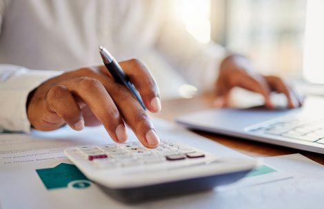 A man on a computer and calculator working out his business budget strategy.