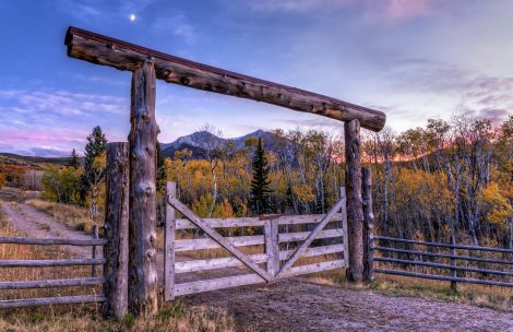 An entry gate to a ranch frames Mount Sopris at sunset near Carbondale, Colorado