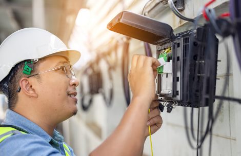 An internet technician is repairing or maintaining a fiber optic connection by opening a fiber optic connector.