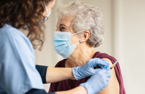 Doctor giving injection to senior woman at hospital. Nurse holding syringe and using cotton before the Covid-19 or coronavirus vaccine.