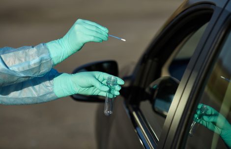 Coronavirus test station. Medical worker in full protective gear takes sample from patient at a COVID-19 drive-thru test site. Testing is done by swab.