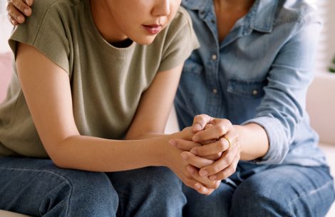 Middle aged Asian people holding hands, building trust and comfort to help young woman with stress relief at home.