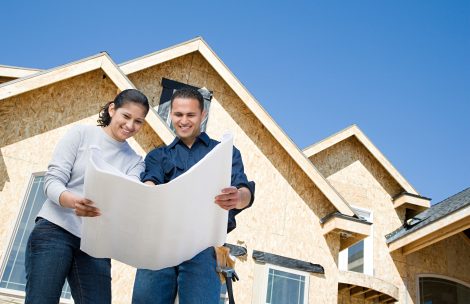 A couple looking at a blueprint in front of home construction.