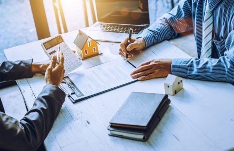 Real-estate agent sign for home contract property for sale in the office with buyer.
