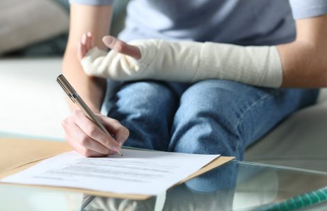 Woman with bandaged arm signing document or survey.
