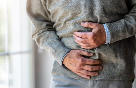 Senior man clutching his stomach in pain.