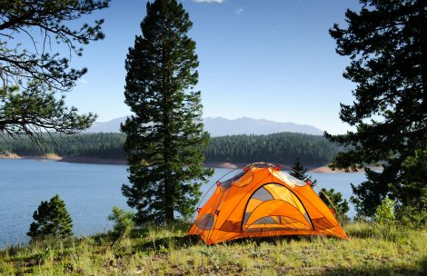 Small orange tent by the mountain lake