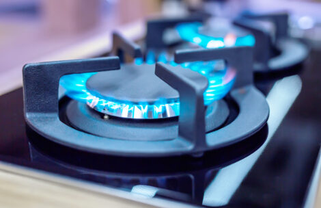 Modern kitchen gas stove with blue flames burning.