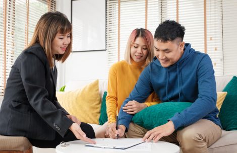 Asian couple sign home contract and handshake with realtor at living room in new home.