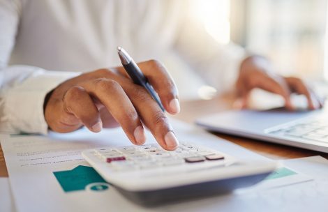 A man on a computer and calculator working out his business budget strategy.