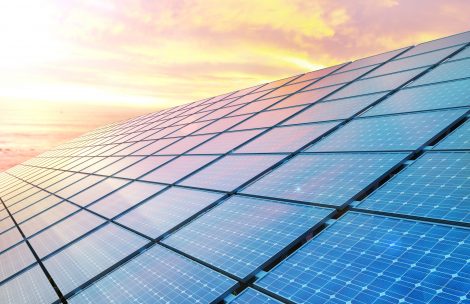 Close up solar panels with the sun setting in the background.