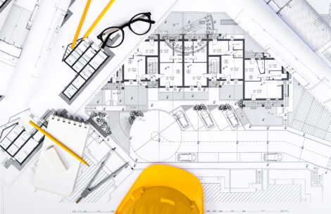 Top view of construction plans with tablet, drawing and working tools on blueprints.