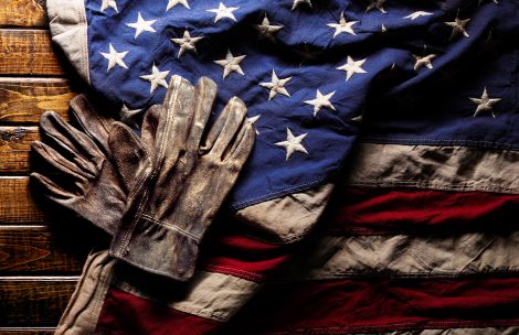 Old and worn work gloves on large American flag.