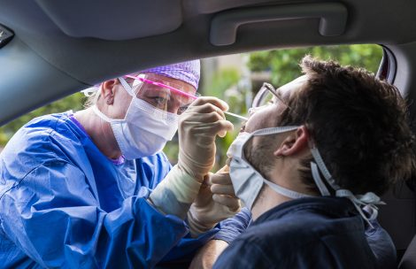 A doctor in a protective suit taking a nasal swab from a person to test for possible coronavirus infection.