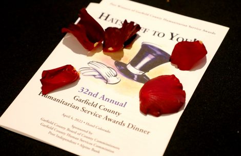 The program for the 2022 Garfield County Humanitarian Awards on a black tablecloth and covered with red rose petals.